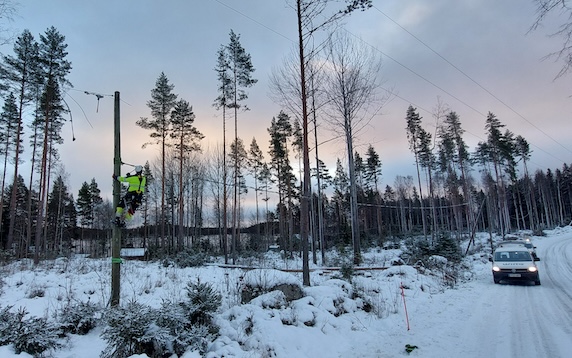 Sähköasentaja on kiivennyt sähkötolppaan korjaamaan ilmajohtoverkon vikaa.